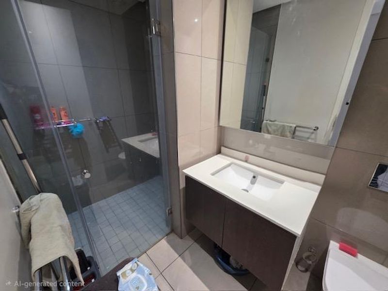 Modern bathroom featuring a vanity cabinet with integrated sink, wall-mounted mirror, glass shower enclosure, and wall-mounted toilet with neutral tiled finishes.