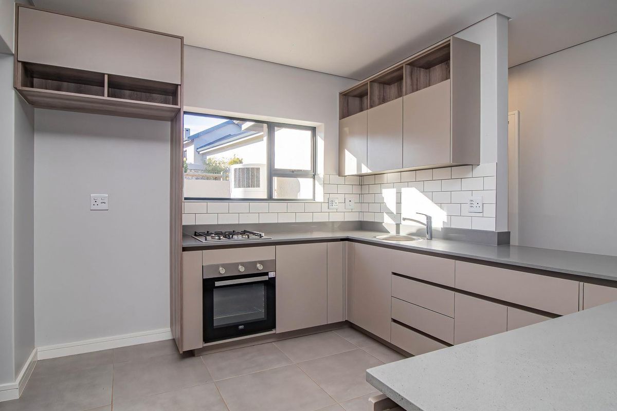 Modern kitchen featuring sleek cabinetry, stone countertops, subway tile backsplash, built-in oven, and gas hob.