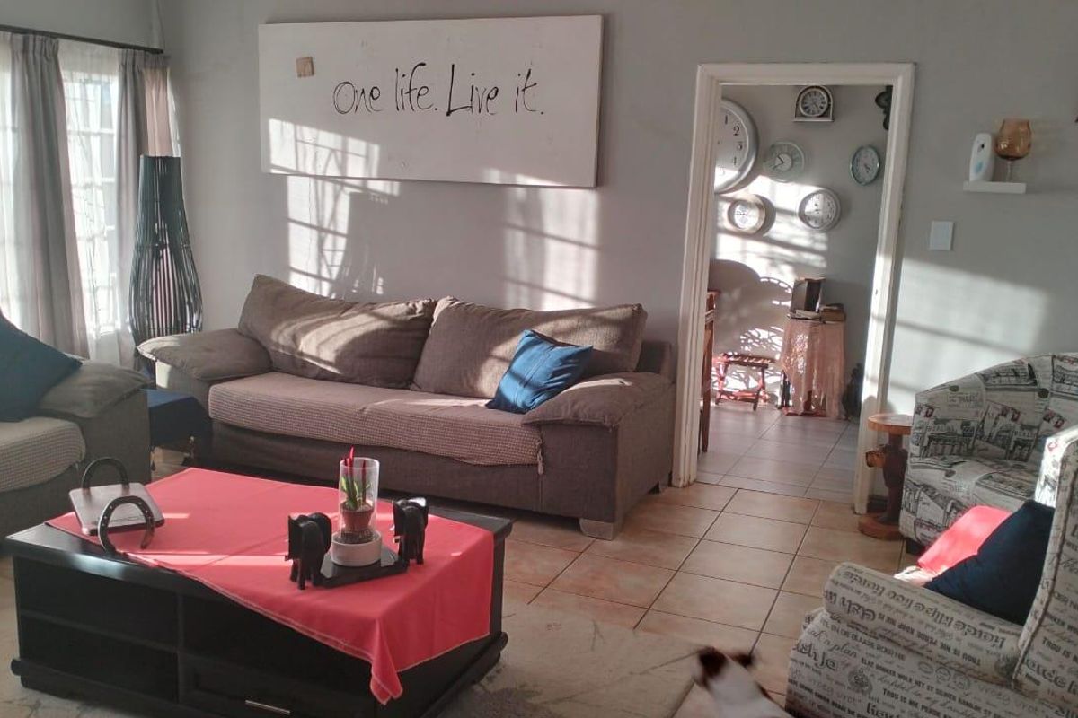 A comfortable living room featuring tiled flooring and a doorway leading to an adjacent space, providing a functional and inviting atmosphere.