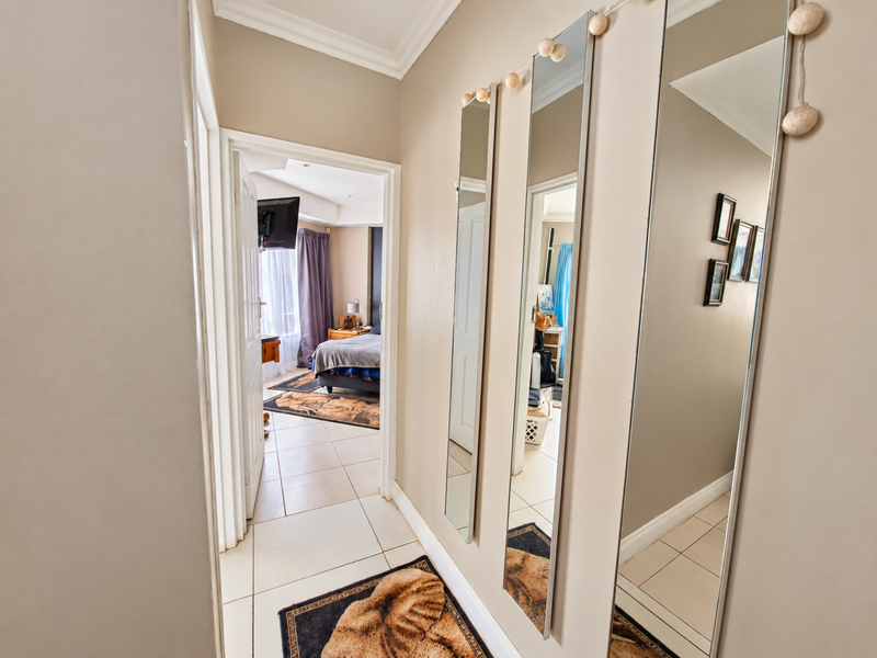 A bright hallway featuring tiled flooring and crown molding, providing access to an adjacent bedroom.