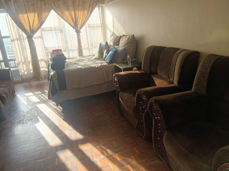 A bedroom featuring parquet flooring and a large window allowing for natural light.