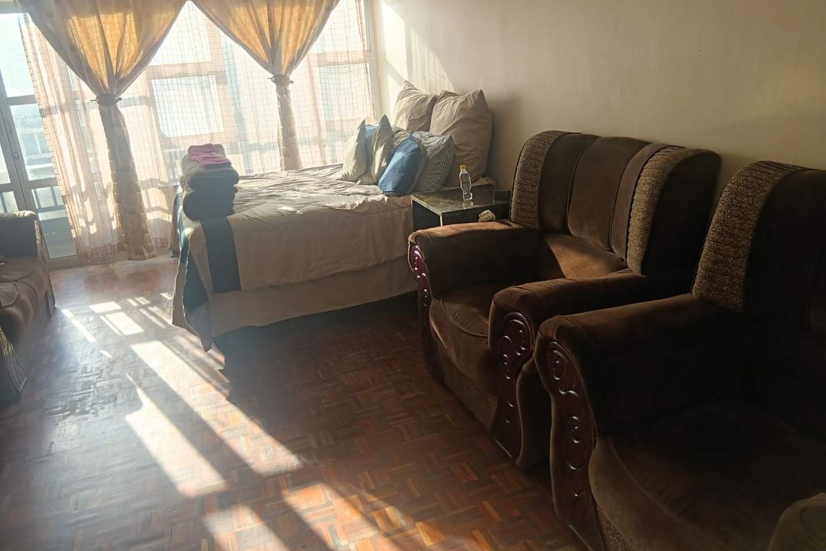 A bedroom featuring parquet flooring and a large window allowing for natural light.