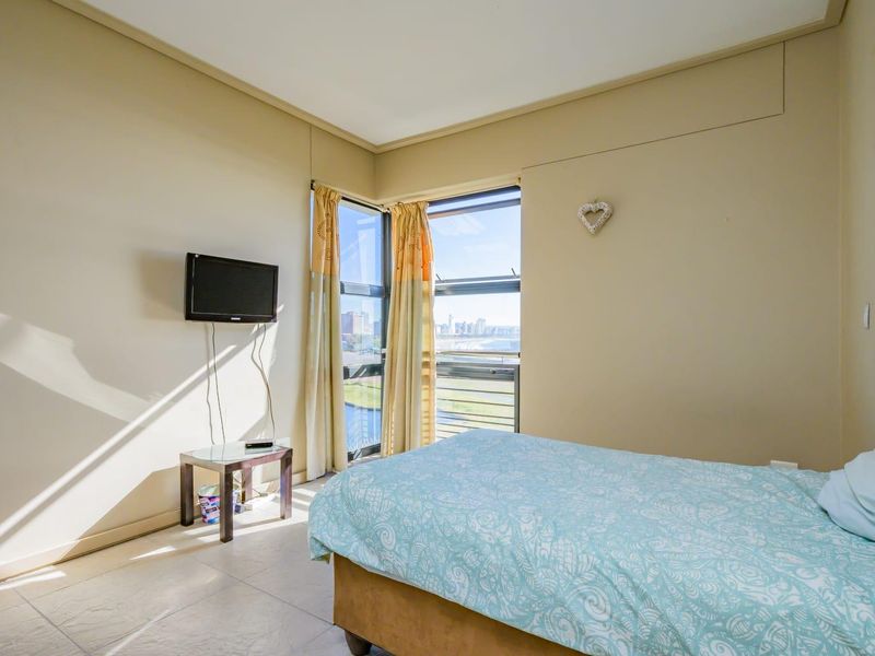 A bedroom featuring tiled flooring and a corner window that provides natural light and views.