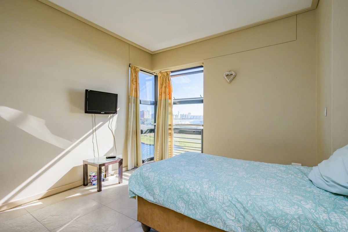 A bedroom featuring tiled flooring and a corner window that provides natural light and views.