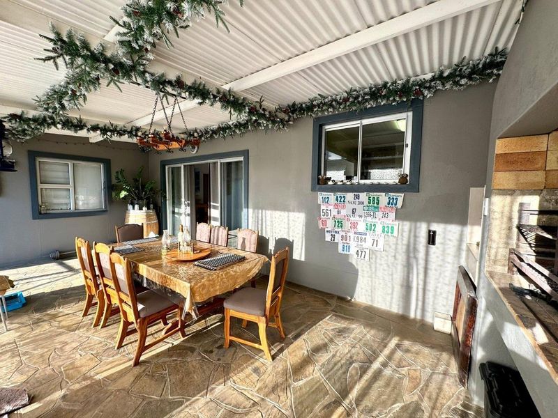 Covered outdoor patio featuring stone flooring, a built-in braai, and sliding door access to the main living area.