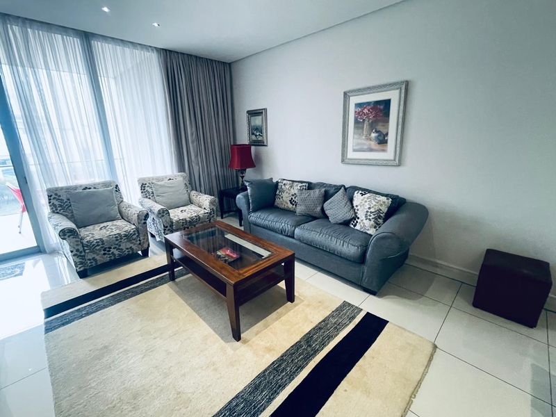A bright and spacious living room featuring large sliding glass doors that provide ample natural light and access to the balcony area.