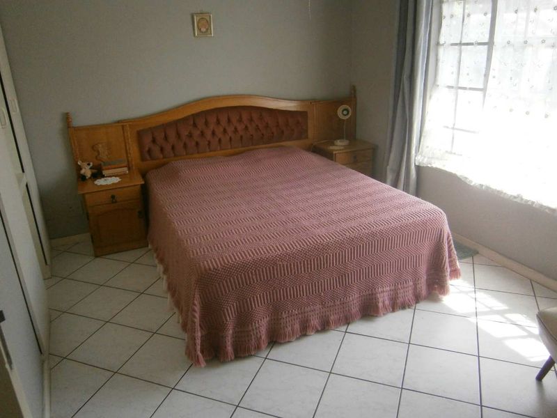 A bedroom featuring tiled flooring and built-in cabinetry with an integrated headboard, offering a functional and dated living space.