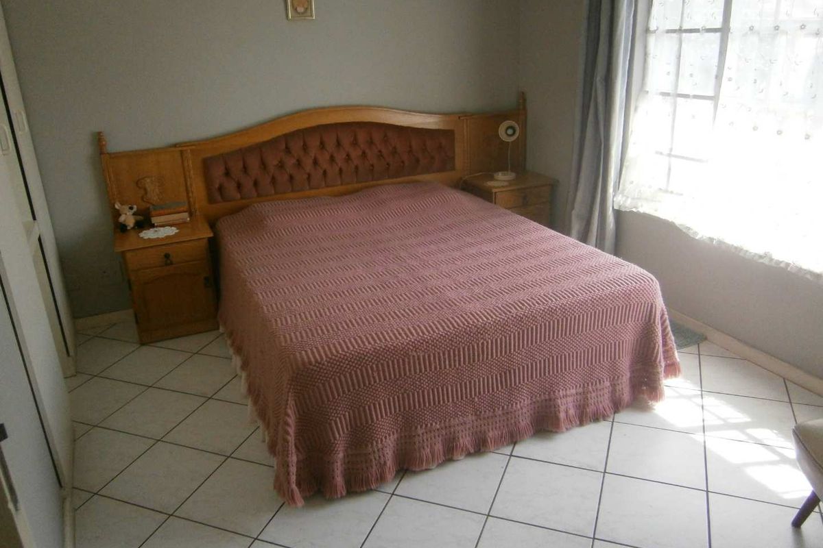 A bedroom featuring tiled flooring and built-in cabinetry with an integrated headboard, offering a functional and dated living space.