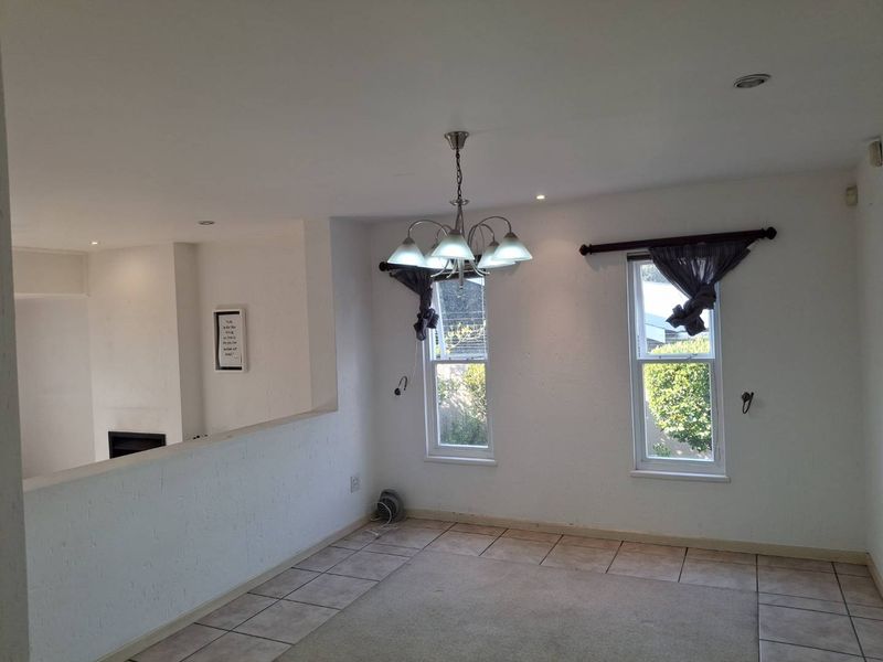 A bright, open-plan living area featuring tiled flooring, a central chandelier, and a built-in fireplace, offering a versatile space for comfortable living.