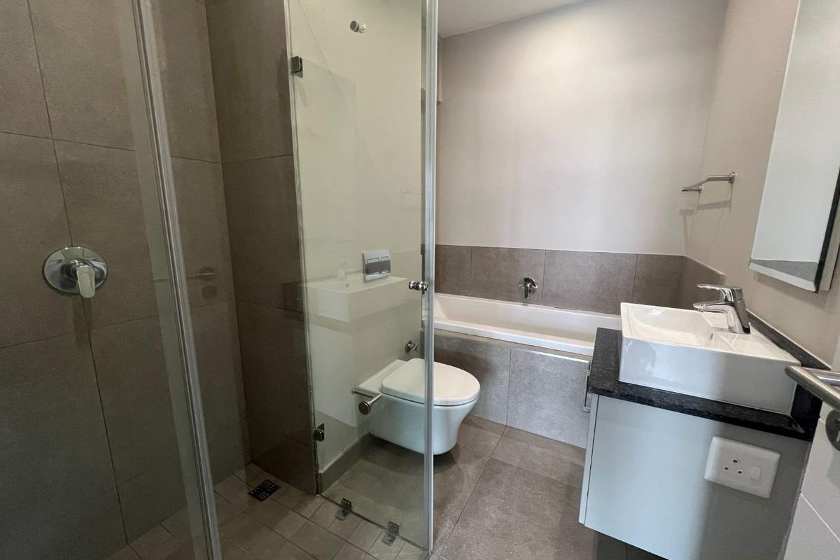 Modern bathroom featuring a glass-enclosed shower, built-in bathtub, wall-mounted toilet, and a sleek vanity with a countertop basin.