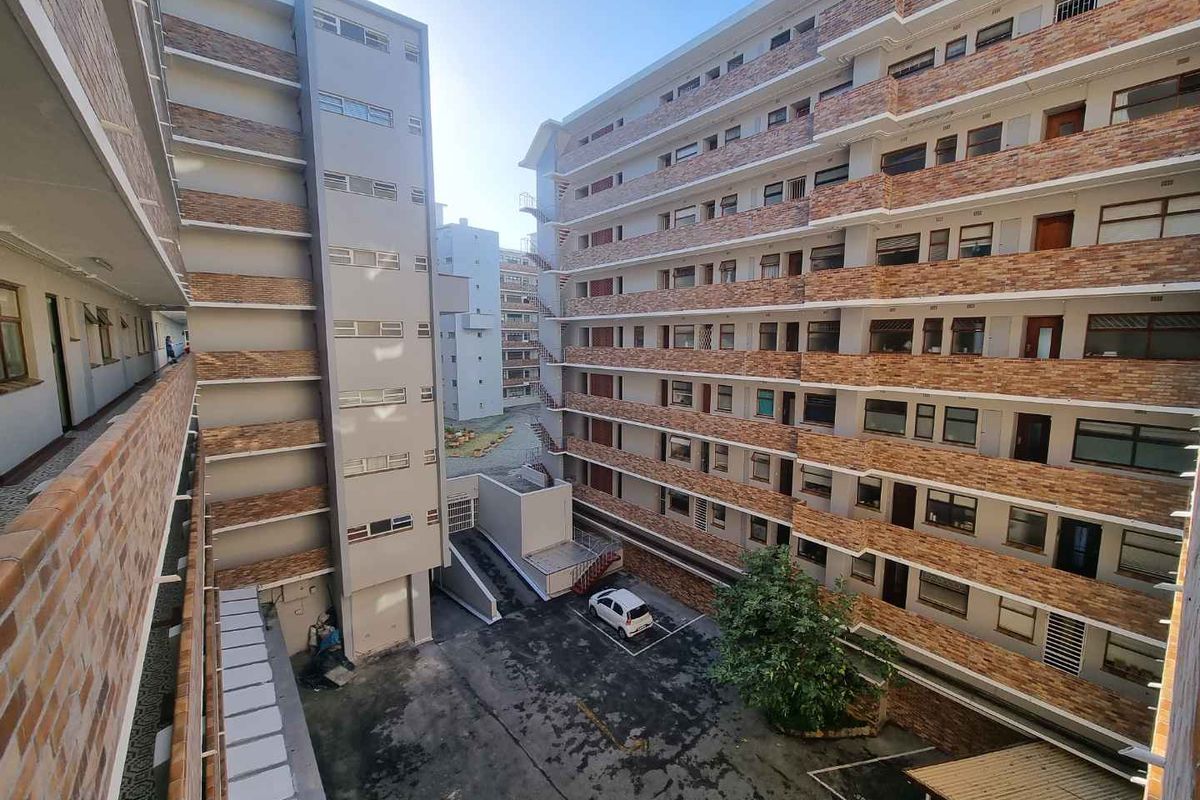 An elevated view of the apartment complex courtyard featuring brick facades, concrete walkways, and designated parking areas.