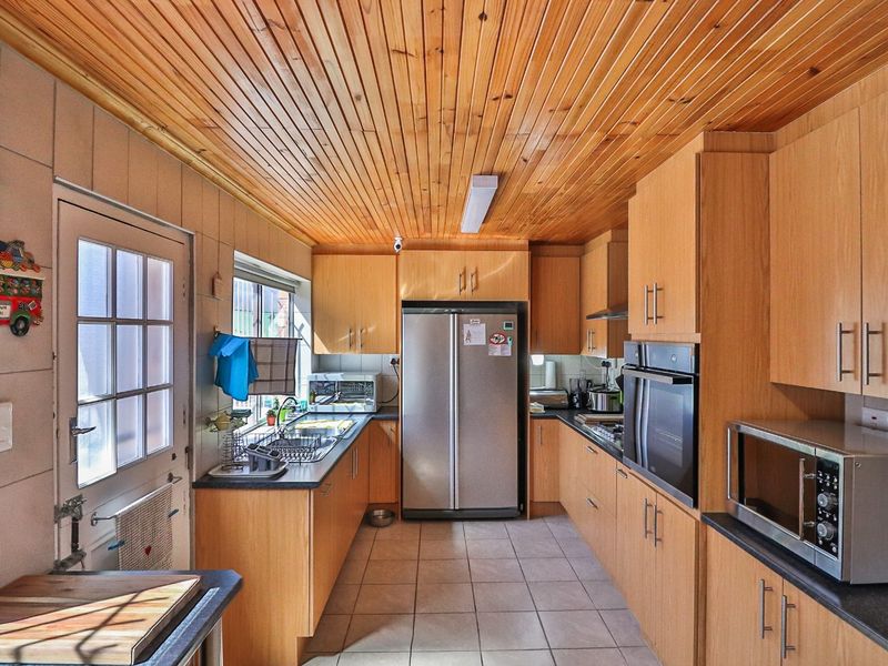 Functional kitchen featuring timber ceiling, ample built-in cabinetry, laminate countertops, and integrated oven, providing a practical workspace with tiled flooring.