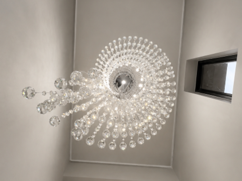 A dramatic double-volume entrance hall featuring a large crystal chandelier, high ceilings, and a skylight that floods the space with natural light.