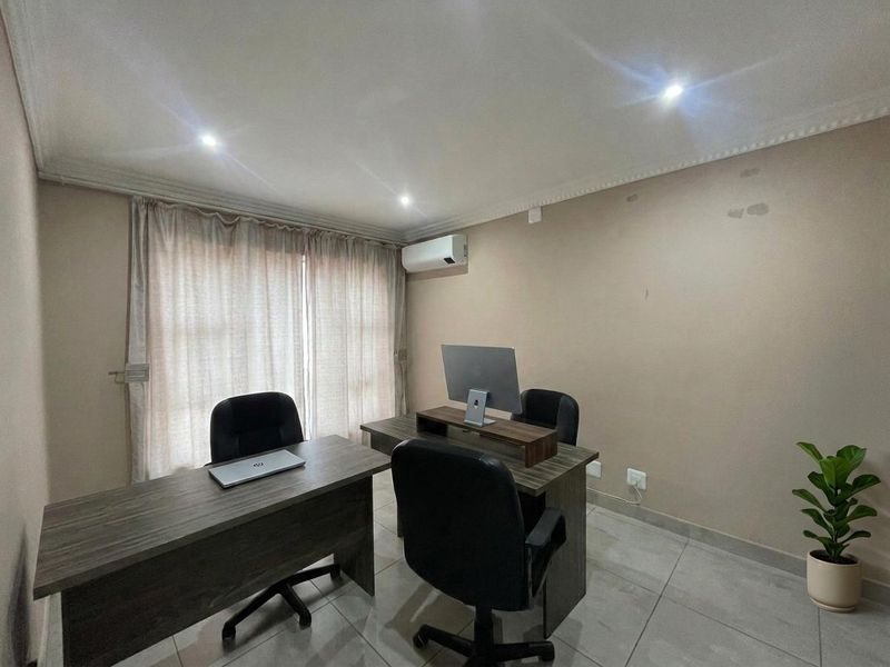 A functional home office space featuring tiled flooring, recessed lighting, and a wall-mounted air conditioning unit.