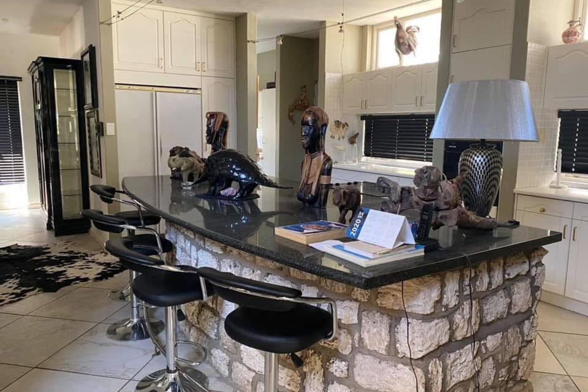 Spacious kitchen featuring a large stone-clad breakfast bar, granite countertops, and white cabinetry, offering a functional layout for cooking and casual dining.