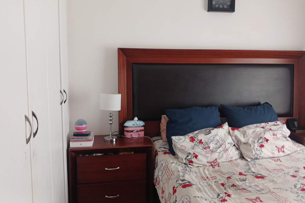 A bedroom featuring built-in cupboards and a dark wood headboard.