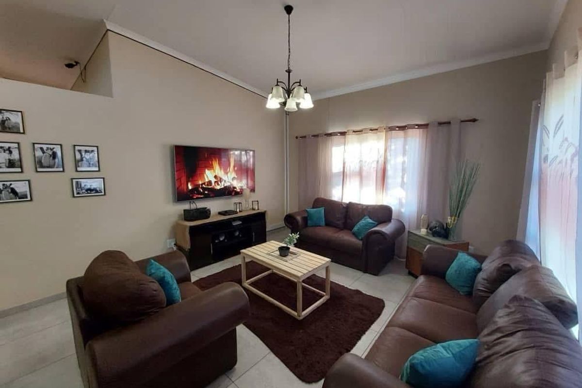 A spacious living room featuring tiled flooring, high ceilings, and large windows that allow for natural light.