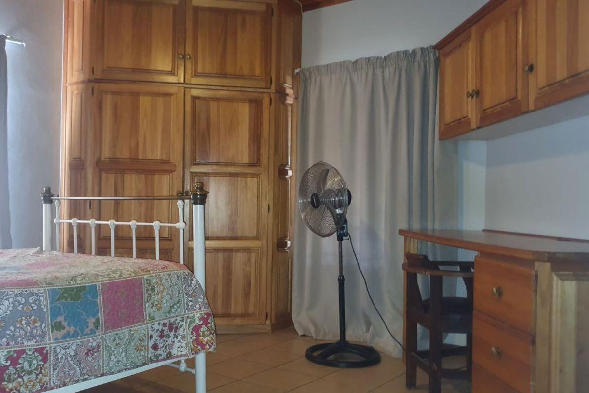 A bedroom featuring built-in wooden cabinetry and a matching built-in desk unit with overhead storage cupboards.