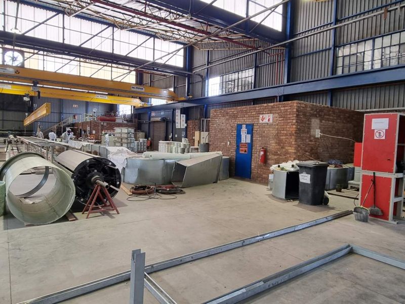 Spacious industrial warehouse facility featuring high ceilings, overhead gantry cranes, and durable concrete flooring, suitable for manufacturing or large-scale storage operations.