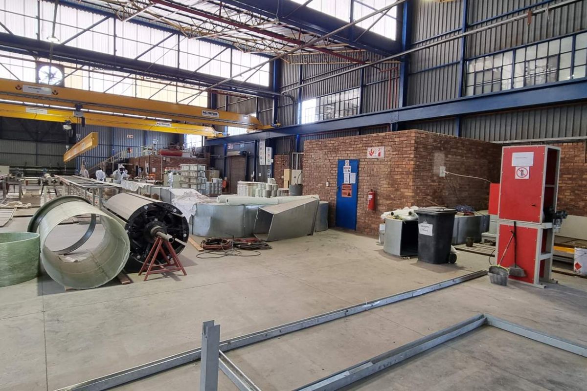 Spacious industrial warehouse facility featuring high ceilings, overhead gantry cranes, and durable concrete flooring, suitable for manufacturing or large-scale storage operations.