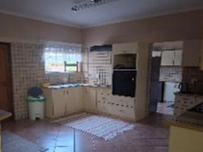 A dated kitchen featuring built-in cabinetry, tiled backsplash, and tiled flooring, offering significant potential for modernization and renovation.