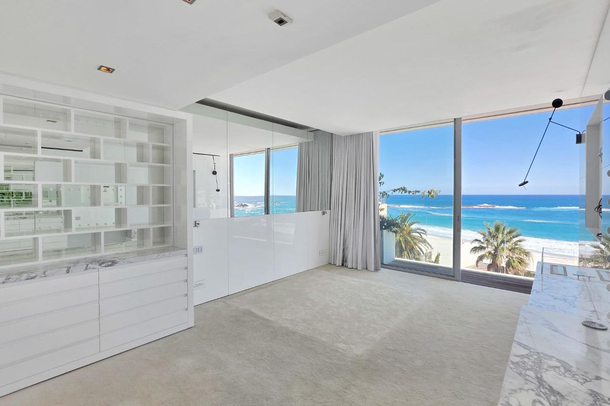 Spacious bedroom featuring custom built-in cabinetry, marble finishes, and expansive floor-to-ceiling windows offering panoramic ocean views.