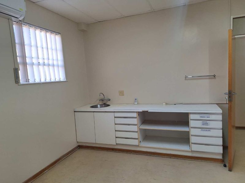 A functional utility space featuring built-in cabinetry, a stainless steel sink, and a wall-mounted air conditioning unit.