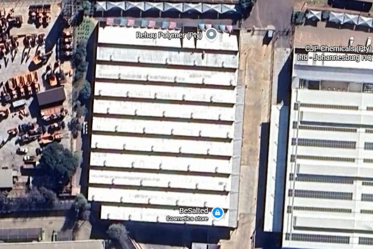 Aerial view of an industrial warehouse facility featuring a large corrugated metal roof, paved yard area, and direct access to Electron Avenue.