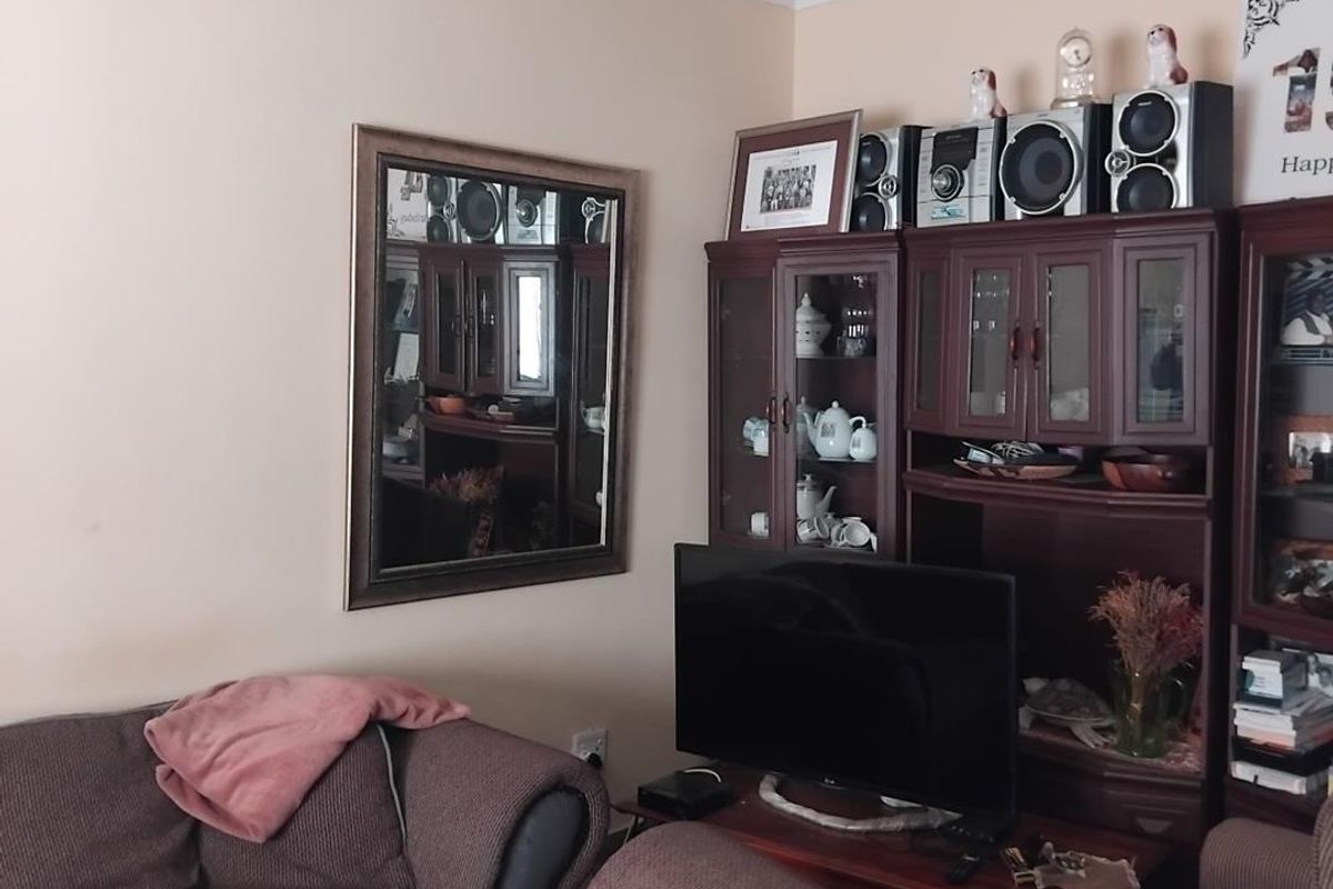 A living room area featuring a wall-mounted mirror and a large built-in wooden display cabinet unit.