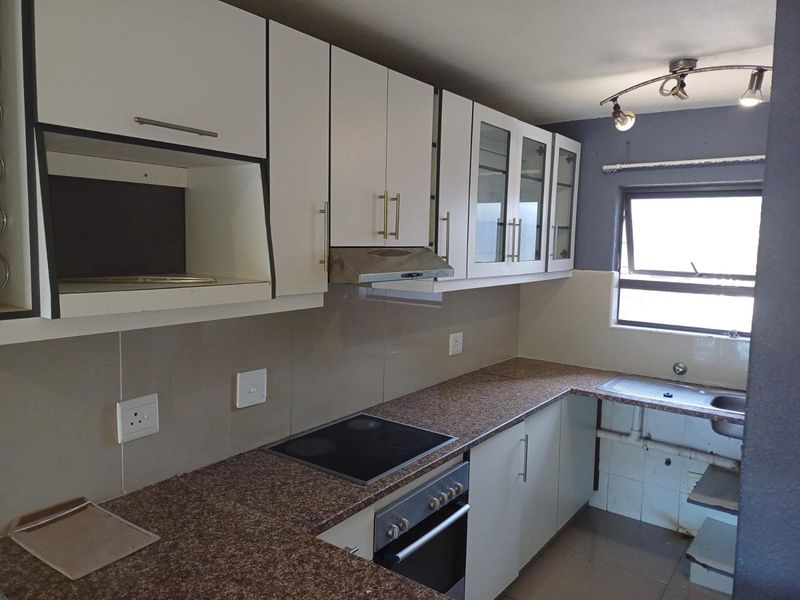 Functional kitchen featuring white cabinetry, granite countertops, built-in oven with hob, extractor fan, and a stainless steel sink with tiled splashback.