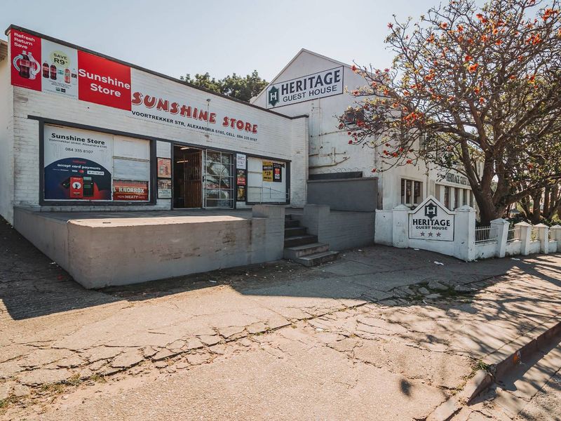 Front exterior view of a commercial property featuring a retail store and guest house with prominent signage and a concrete loading area.