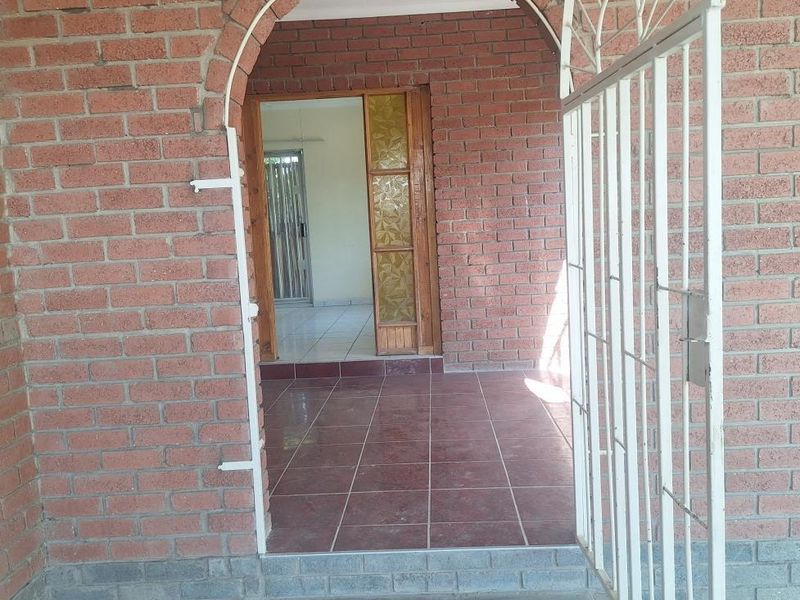 Entrance area featuring an arched brick doorway, metal security gate, and tiled flooring leading into the interior of the home.