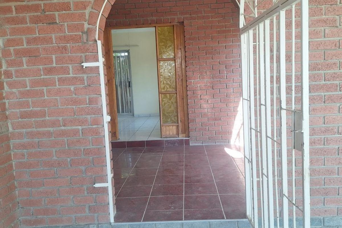 Entrance area featuring an arched brick doorway, metal security gate, and tiled flooring leading into the interior of the home.