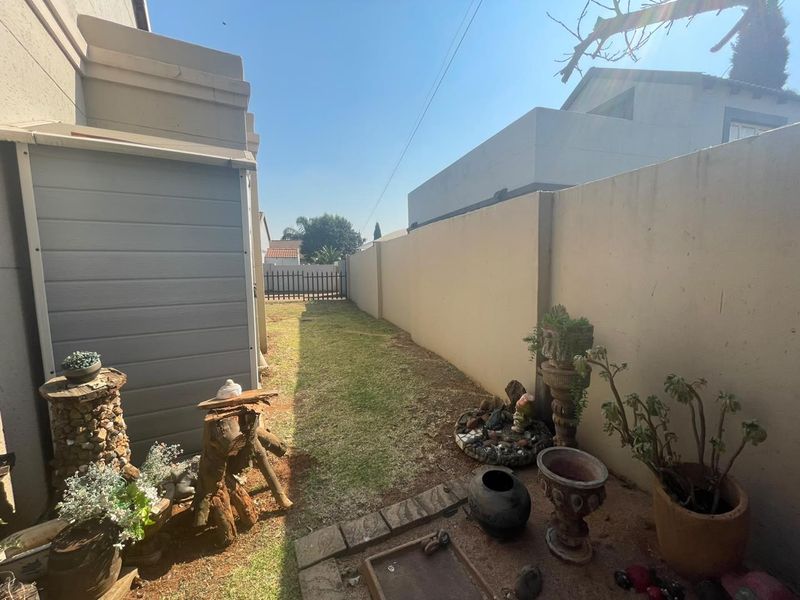 A narrow rear garden area featuring a boundary wall, a small storage shed, and a lawn space requiring maintenance.