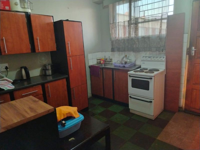 A functional kitchen featuring laminate cabinetry, a stainless steel sink, and a freestanding electric stove with tiled flooring and backsplash.