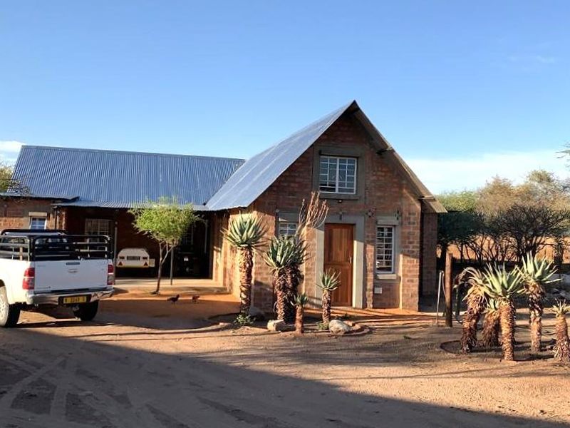A charming farm-style residence featuring exposed brickwork, a corrugated metal roof, and a convenient covered carport area.