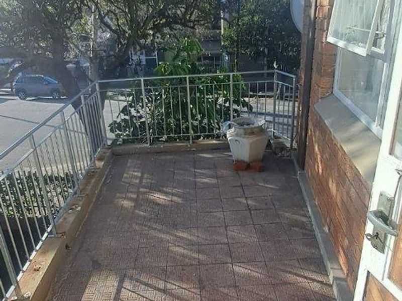 A functional balcony area featuring tiled flooring and a metal balustrade, offering an outdoor space with potential for enhancement.