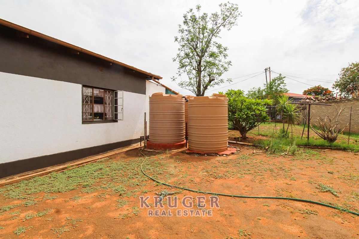 Rear exterior view of the property featuring two large water storage tanks and an unlandscaped yard area.