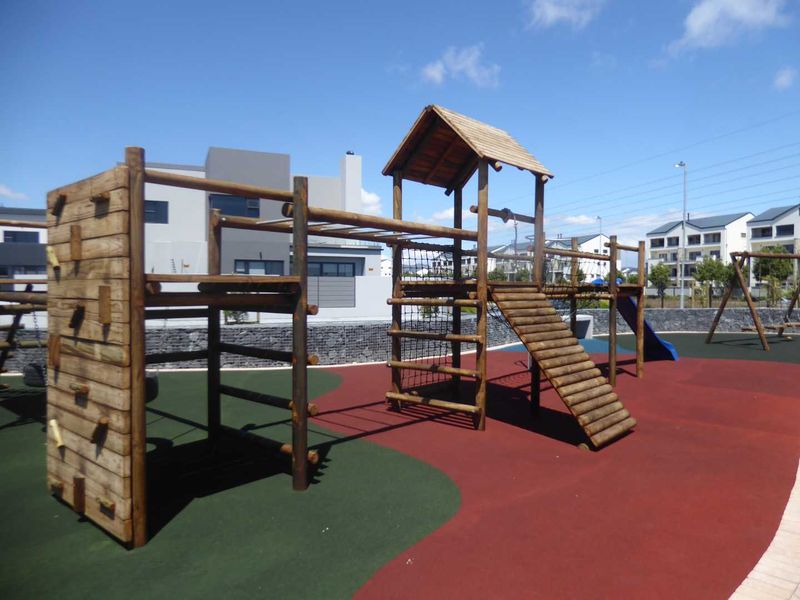 A well-maintained communal playground area featuring a wooden climbing structure, slide, and durable rubberized safety flooring within a residential estate.