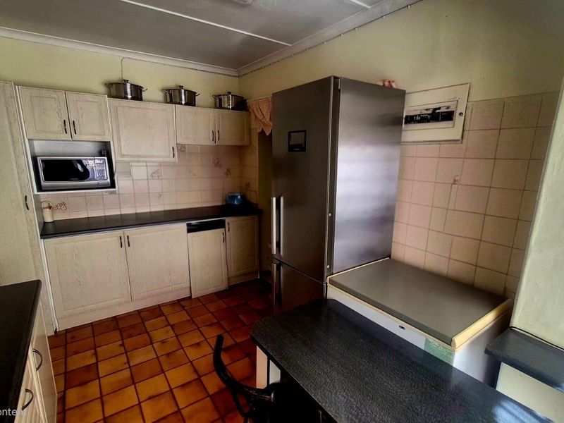 A dated kitchen featuring built-in cabinetry, tiled backsplash, and tiled flooring, offering potential for a modern renovation to enhance functionality and aesthetic appeal.