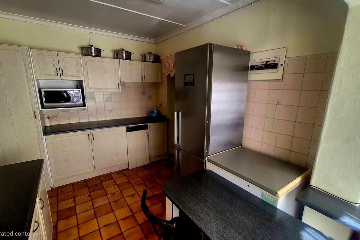 A dated kitchen featuring built-in cabinetry, tiled backsplash, and tiled flooring, offering potential for a modern renovation to enhance functionality and aesthetic appeal.