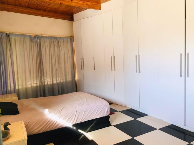 A bedroom featuring built-in cupboards, a timber ceiling, and a distinctive black and white checkered tiled floor.