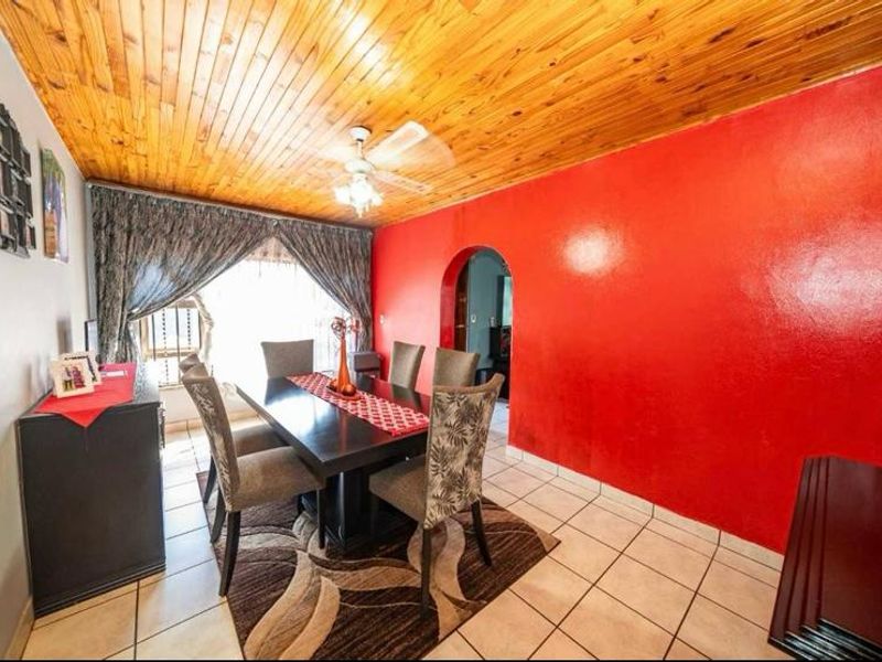 Dining room featuring ceramic floor tiles, a timber tongue and groove ceiling, and a distinctive arched doorway leading to adjacent living spaces.