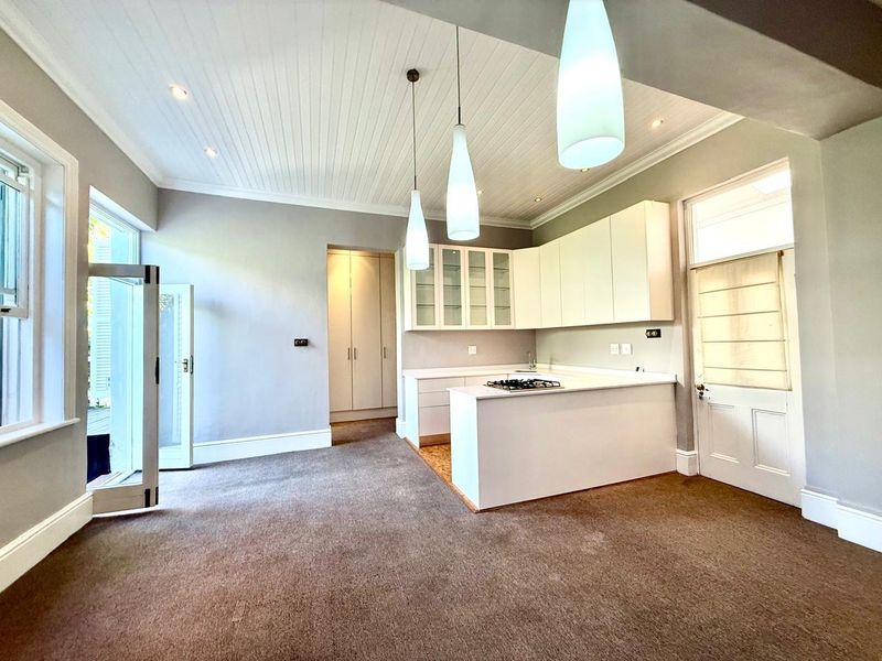 Spacious open-plan living area featuring a modern kitchen with built-in cabinetry, gas hob, pendant lighting, and direct access to an outdoor patio.