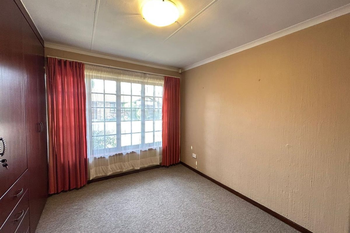 A bedroom featuring built-in cabinetry, carpeted flooring, and a large window with natural light.