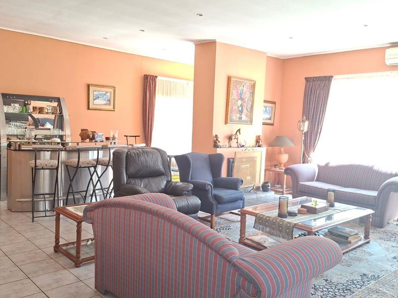 Spacious living area featuring tiled flooring, a built-in fireplace, and a wall-mounted air conditioning unit, offering a comfortable and functional layout.