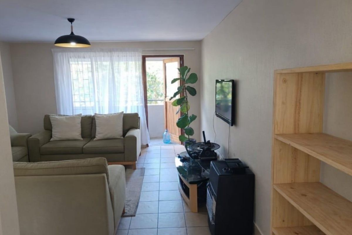 A bright living room featuring tiled flooring, a pendant light, and direct access to an outdoor balcony area through a sliding door.
