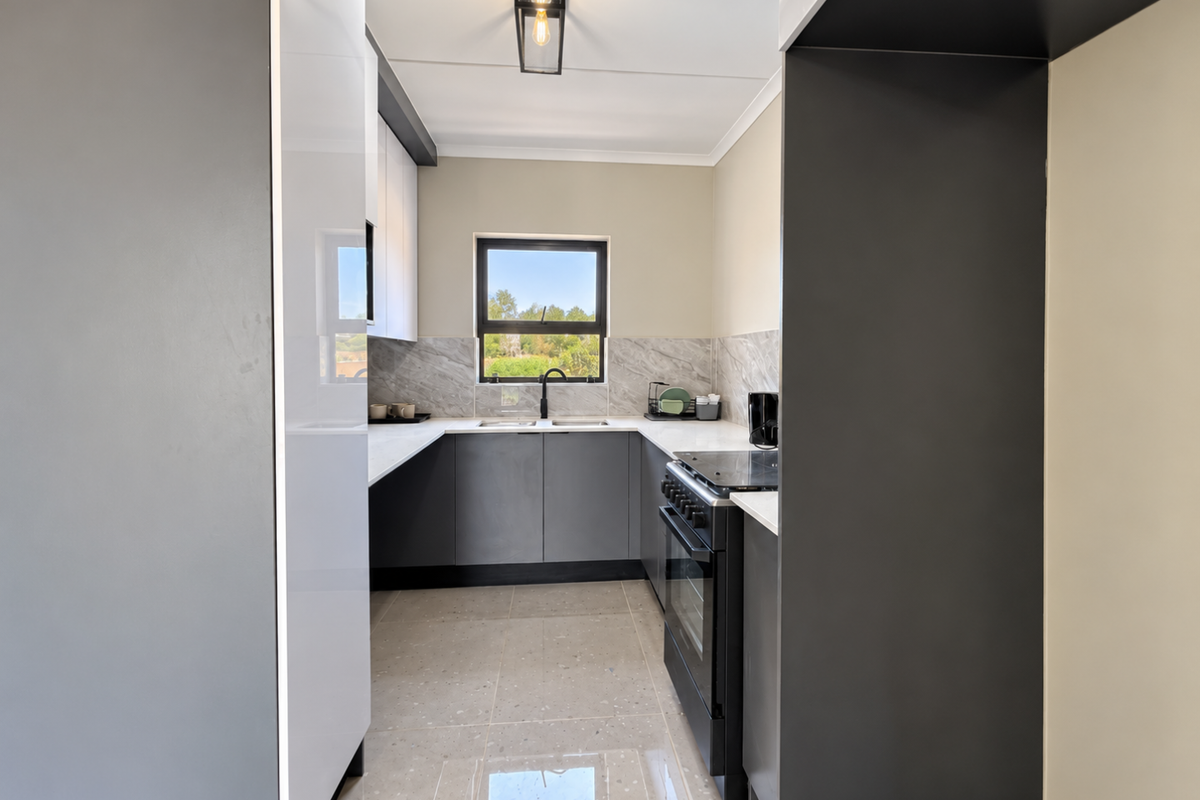 Modern kitchen featuring sleek grey and white cabinetry, stone countertops, marble-look backsplash, and high-quality tiled flooring with a functional layout.