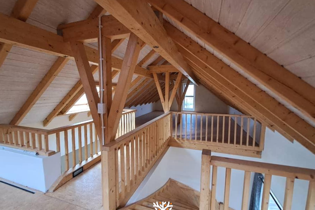 Spacious attic loft area featuring exposed timber roof trusses, wooden balustrades, and natural light, offering potential for a versatile living space or bedroom.