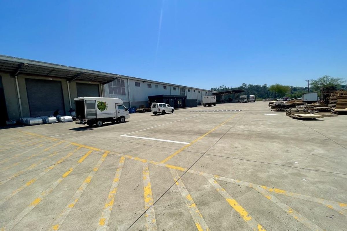 Expansive industrial concrete yard featuring multiple roller shutter doors, loading bays, and ample space for heavy vehicle maneuvering and logistics operations.